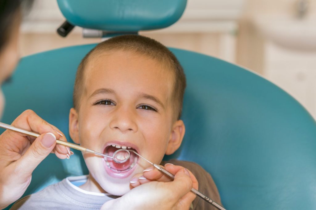 A young boy is getting his teeth brushed